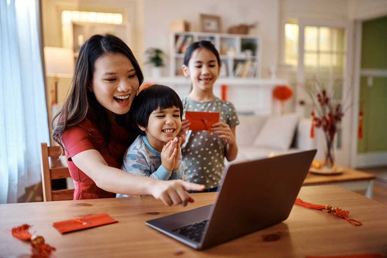 Mom points at laptop while teaching two children about Chinese cultures for kids.