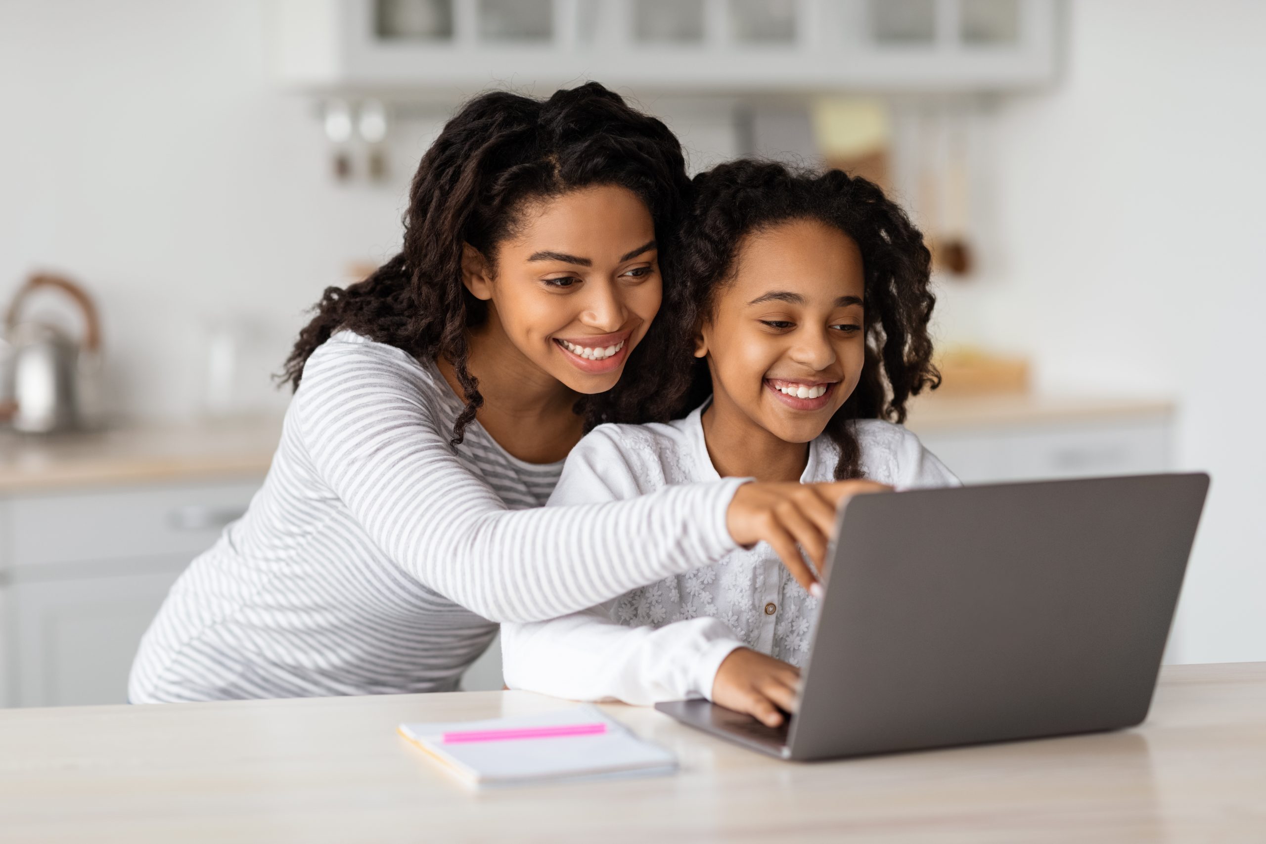 A mom and daughter sit at a laptop to set goals for learning a language.